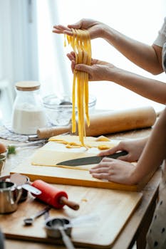 Hands crafting fresh pasta dough in a warm kitchen setting. Perfect for food enthusiasts.
