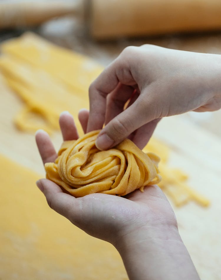 Woman Making Homemade Raw Pasta Nest In Kitchen