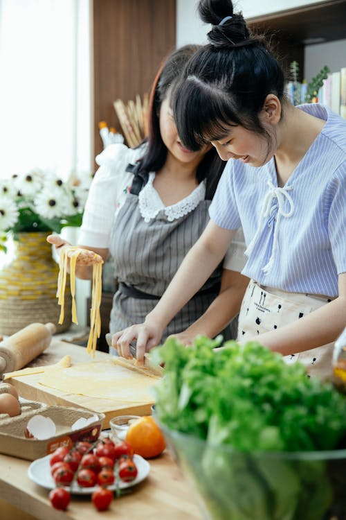 Free Mother teaching daughter to cook homemade noodles Stock Photo