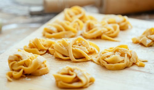 High angle of raw homemade pasta nests on floured wooden board in kitchen