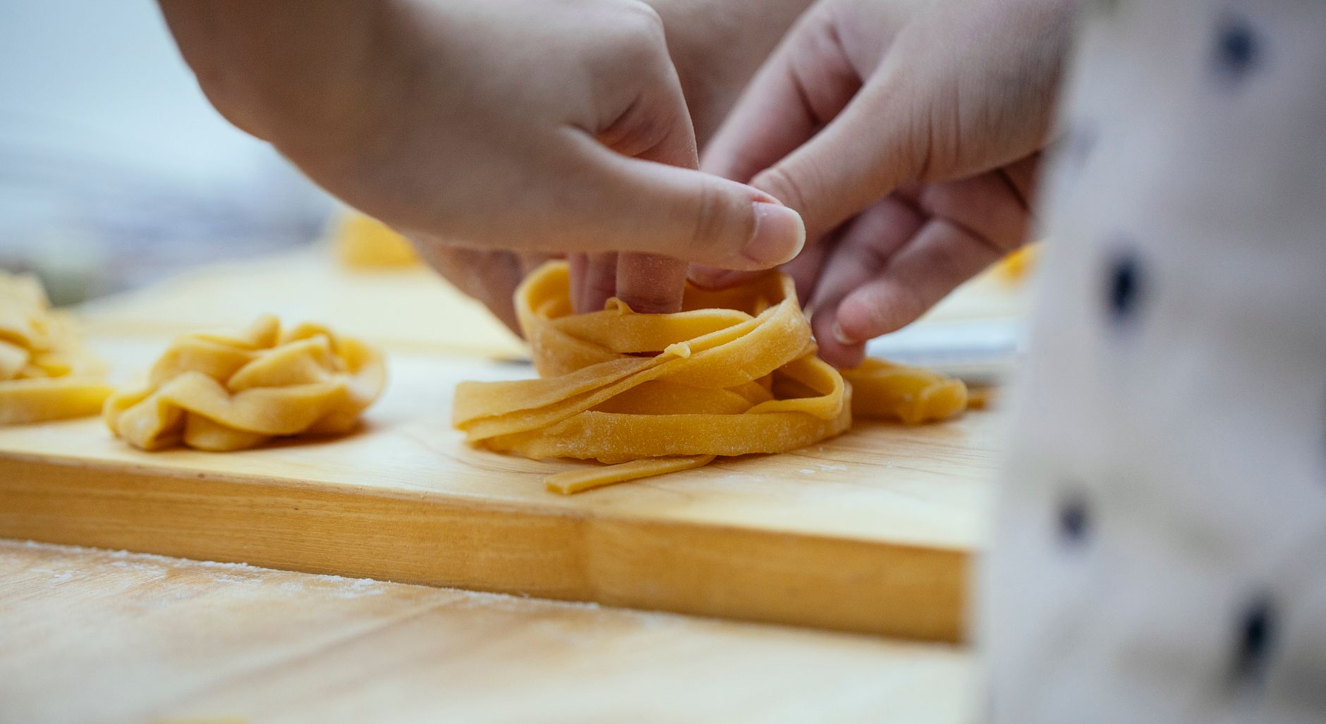 Cut tagliolini and tagliatelle pasta on wooden table