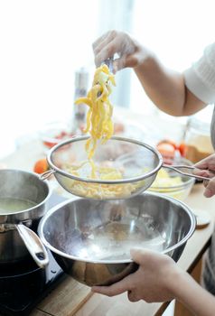 A person preparing fresh homemade pasta with steam in a modern kitchen setting.