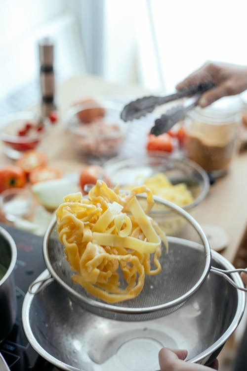 Free Crop person cooking pasta in kitchen Stock Photo
