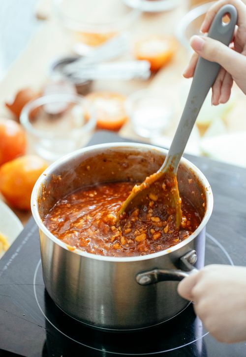 Free Unrecognizable cook with spoon stirring hot chili in pan while standing near stove in kitchen on blurred background during cooking process Stock Photo