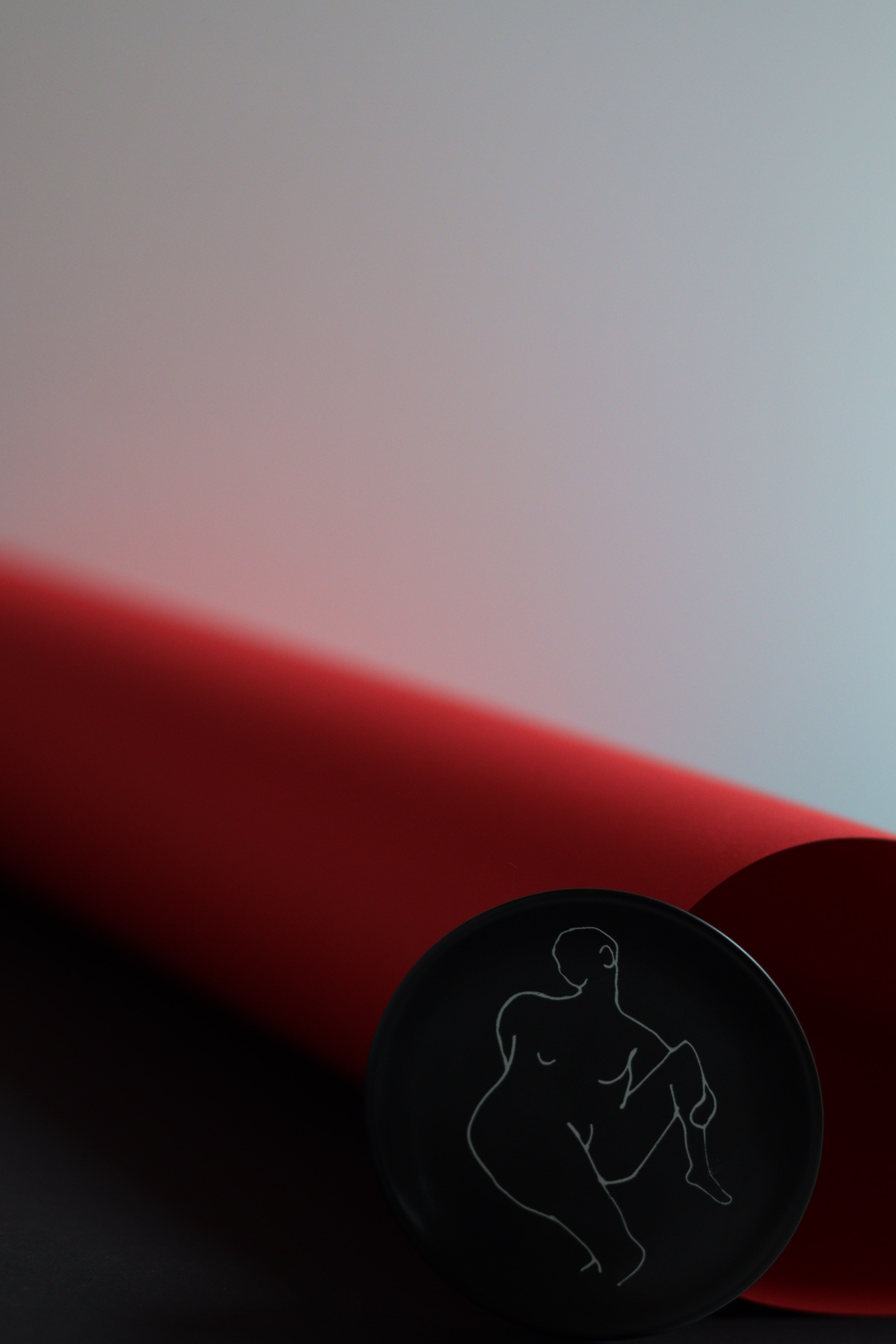 Artistic black button with minimalistic outline drawing, set against a striking red backdrop.