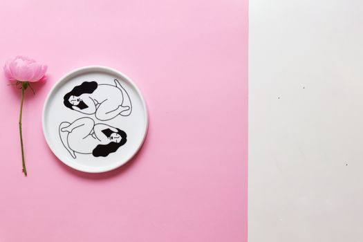 这件极简主义艺术作品在柔和背景上用粉色玫瑰在盘子上描绘了女性形态