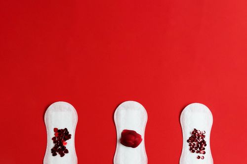 Free Creative display of menstrual pads adorned with heart-shaped symbols on a red background. Stock Photo
