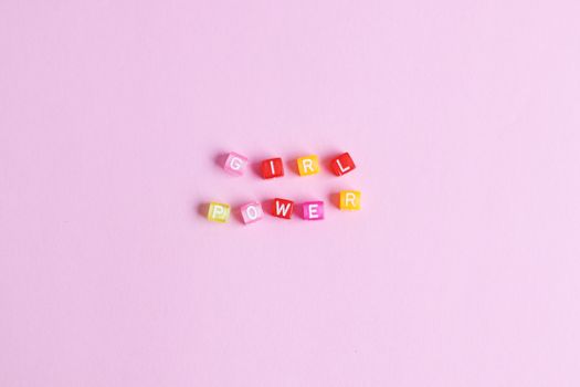 Colorful letter blocks spelling 'Girl Power' on a pink background, emphasizing empowerment.