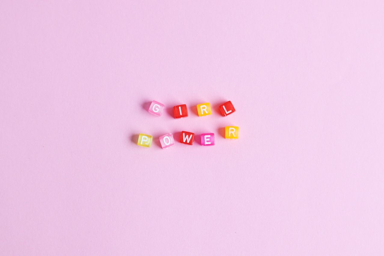 colorful letter blocks spelling girl power on a pink background emphas