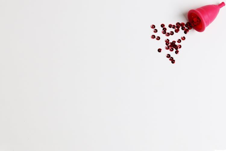 Menstrual Cup With Red Glitters On White Background