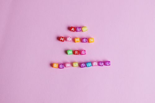 Free A vibrant image with a feminist message spelled out using colorful beads on a pink background. Stock Photo