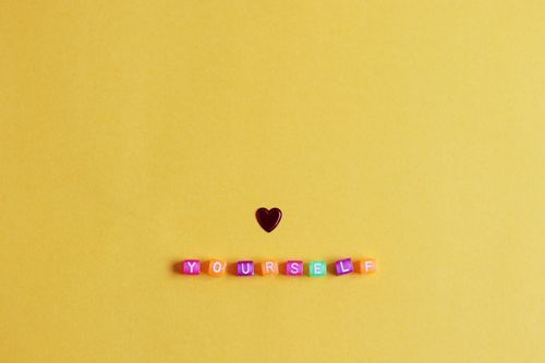Free Bright minimalist arrangement with a heart and 'YOURSELF' on yellow background. Stock Photo