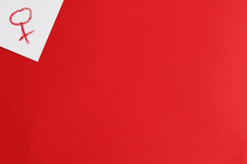 Free Venus symbol on white paper over red background. Ideal for concepts on feminism and women's rights. Stock Photo