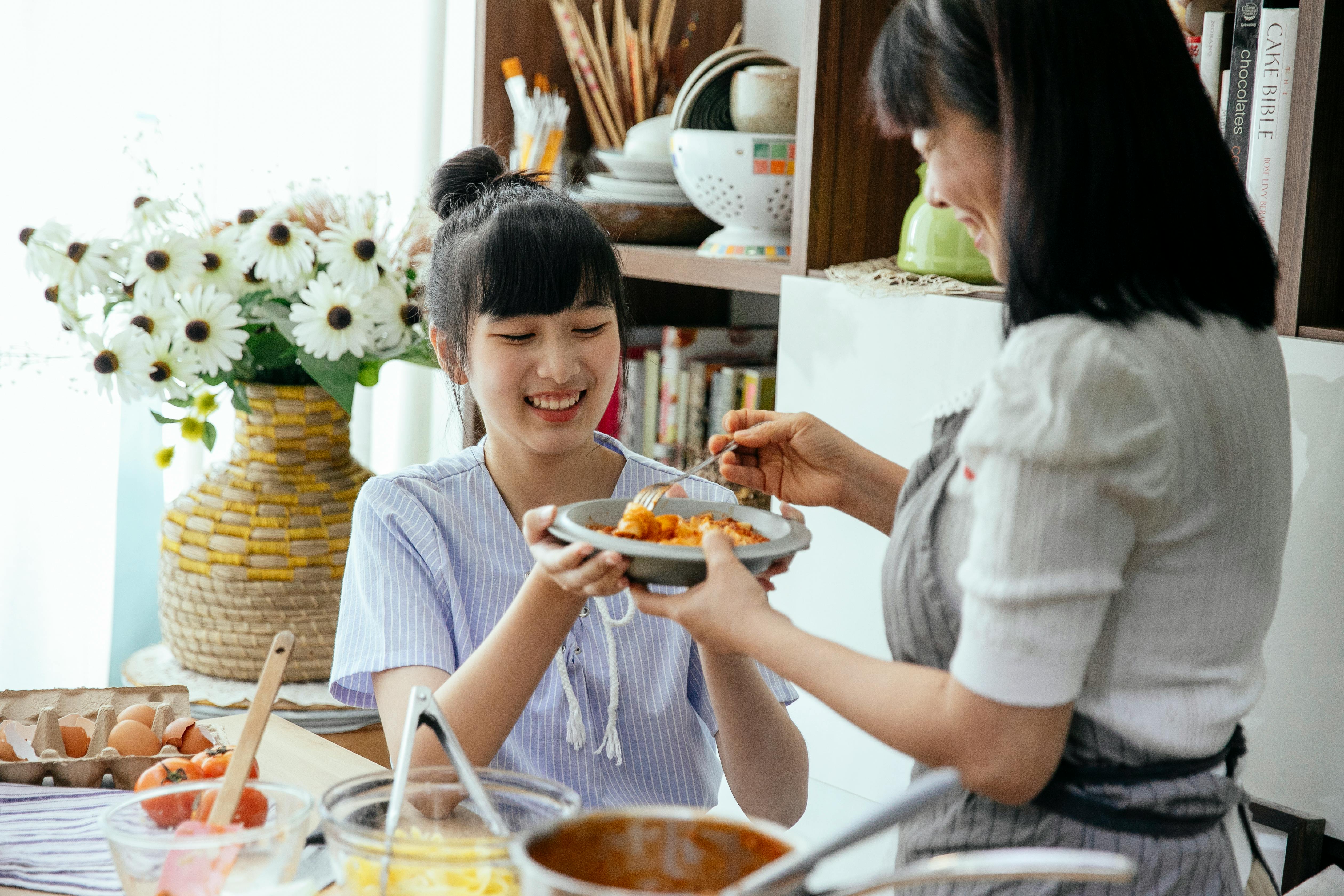 happy ethnic women cooking pasta