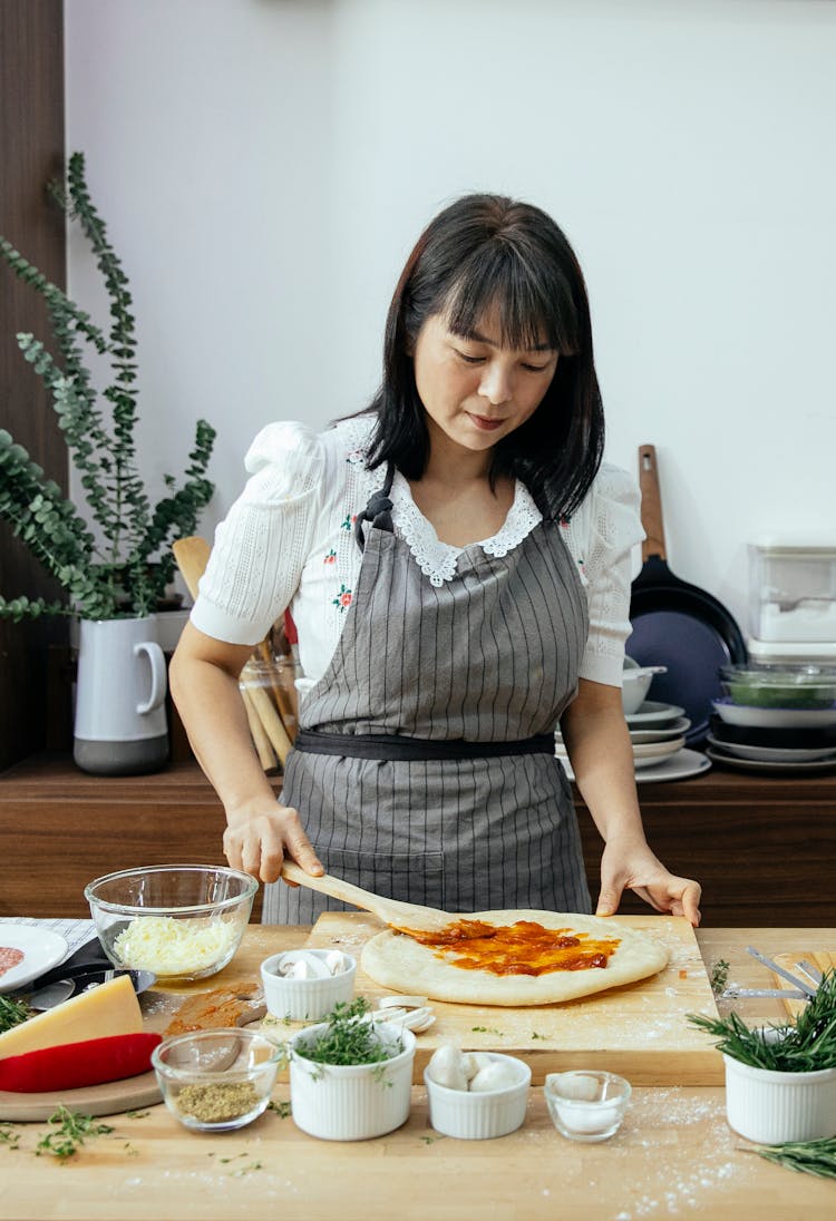 Middle Aged Ethnic Woman Cooking Pizza