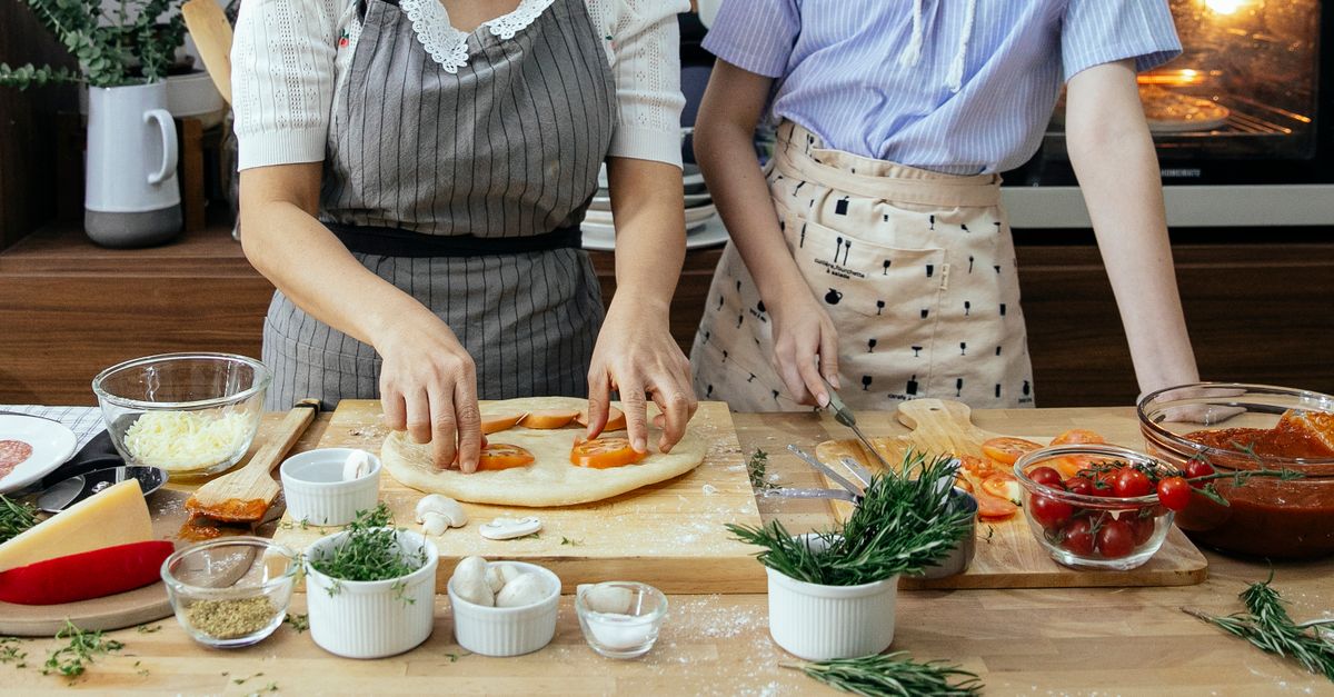 Ho women cooking together in an outdoor shared kitchen with colorful ingredients