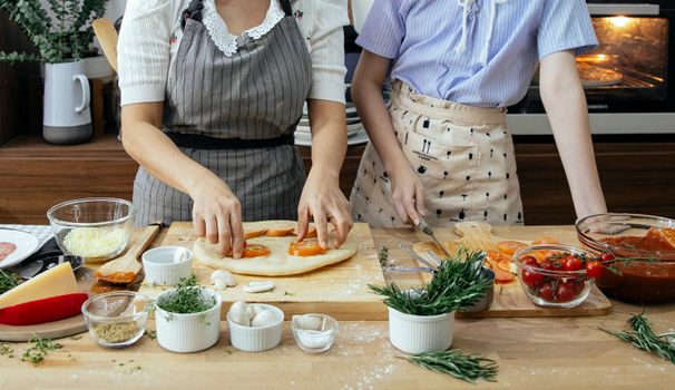母女俩亲密地准备着用新鲜食材自制的披萨