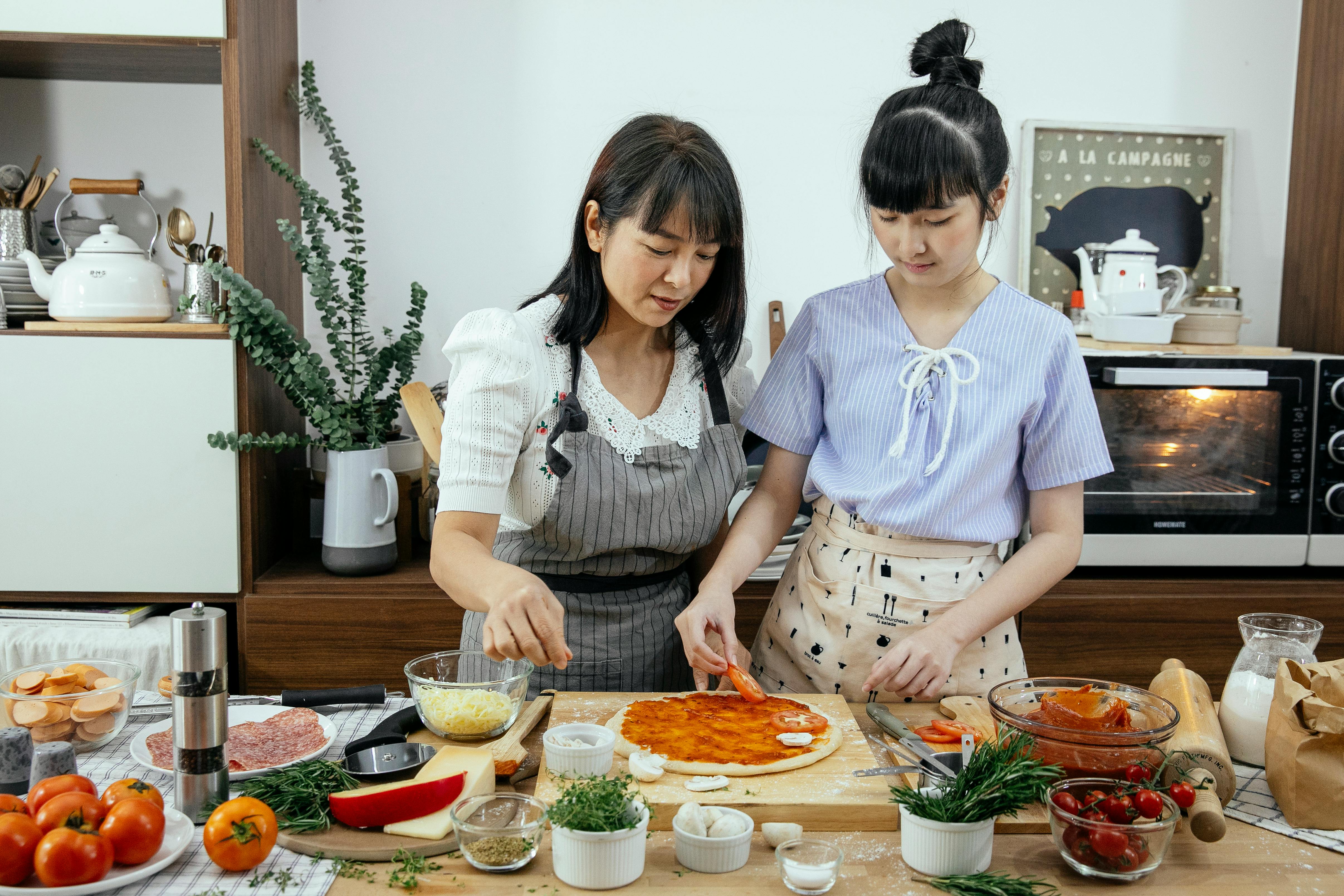 calm ethnic women cooking pizza