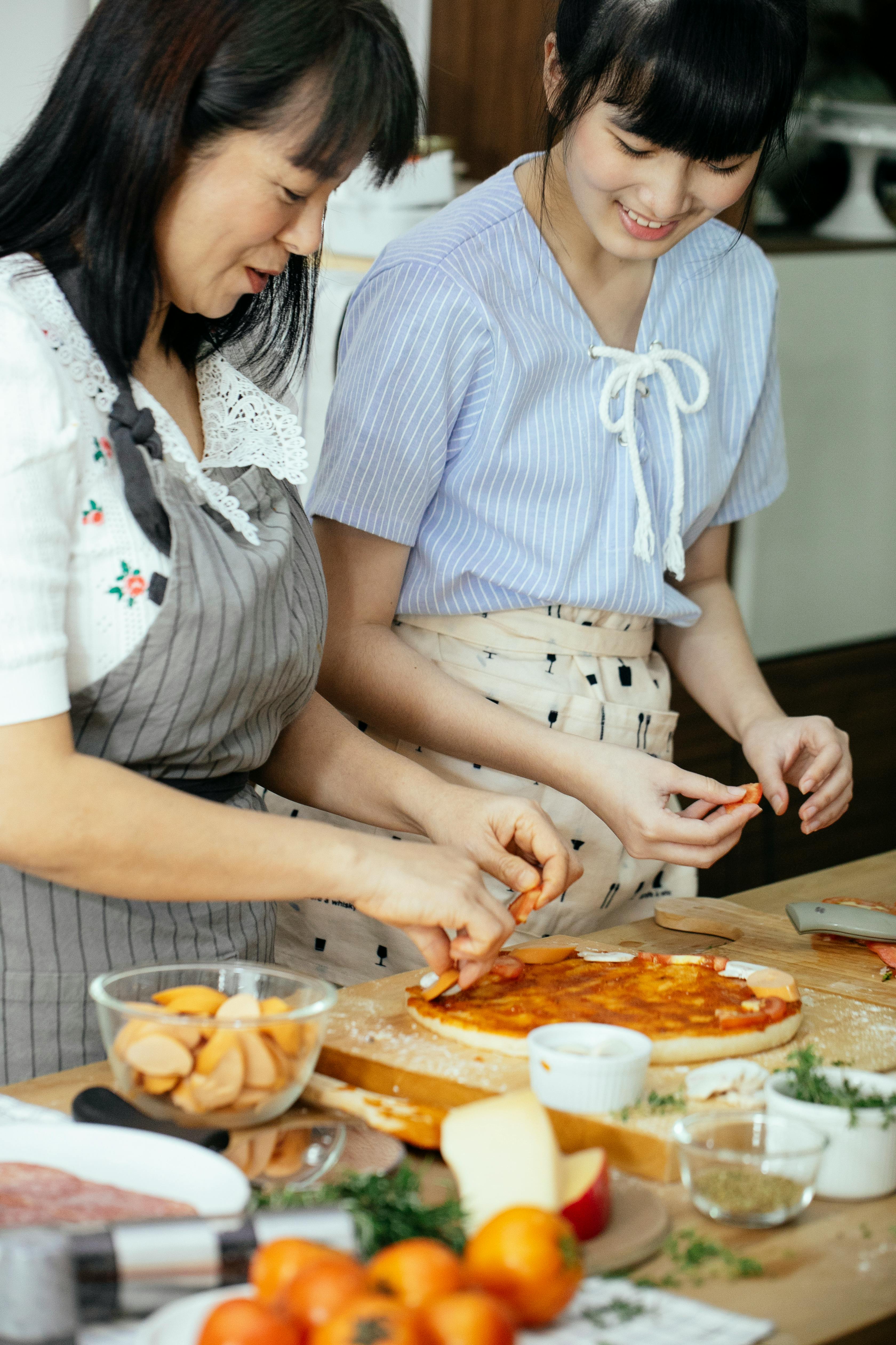 ethnic women on kitchen cooking pizza together