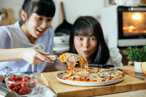 Two Ladies posing a homemade pizza