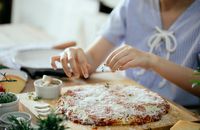 Woman making pizza in kitchen