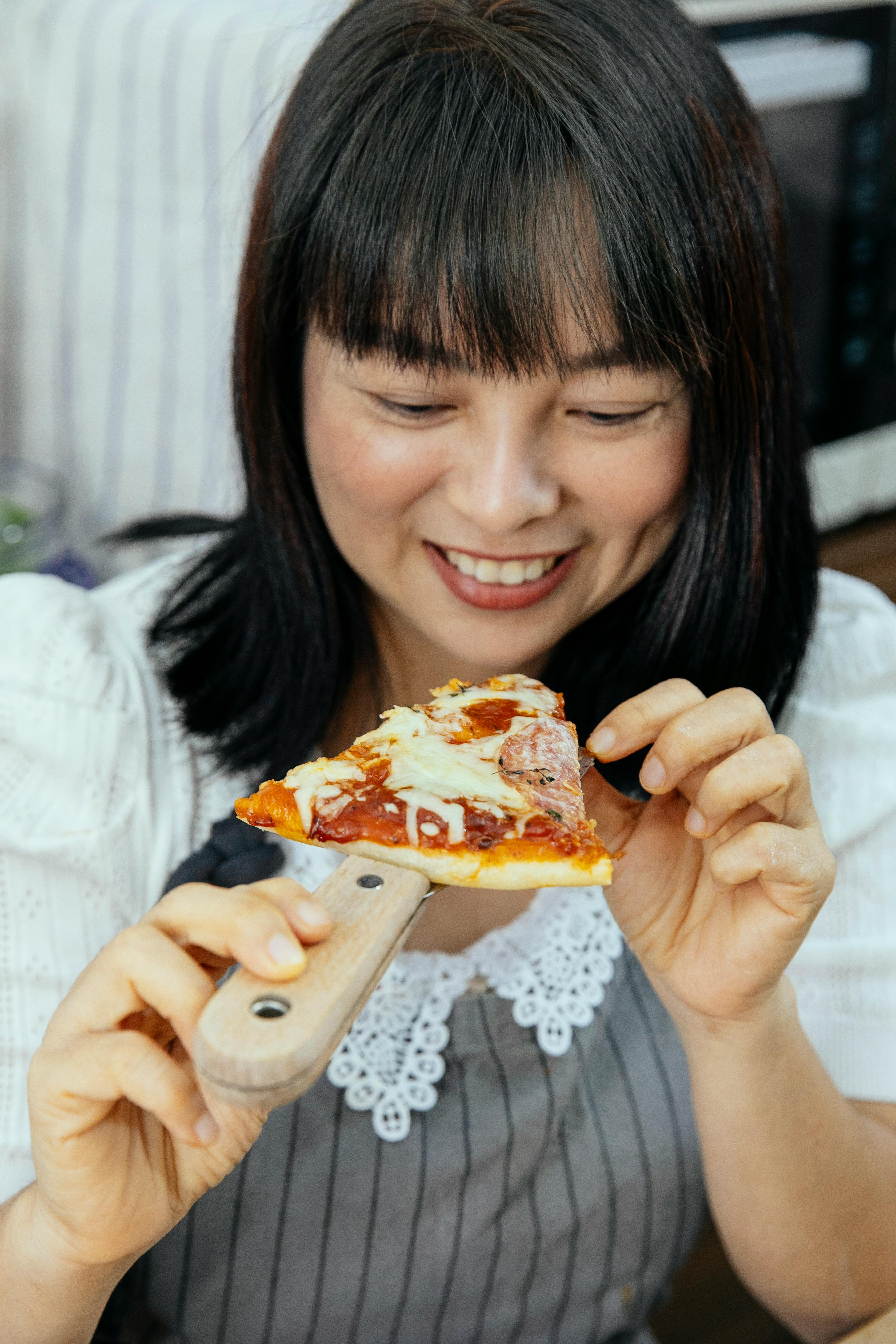 asian woman enjoying tasty pizza