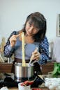 Happy Asian woman boiling noodles in modern kitchen