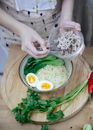 High angle crop anonymous female adding chopped meat into bowl with delicious noodle soup with eggs and pak choi cabbage