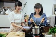Joyful Asian women boiling homemade noodles together