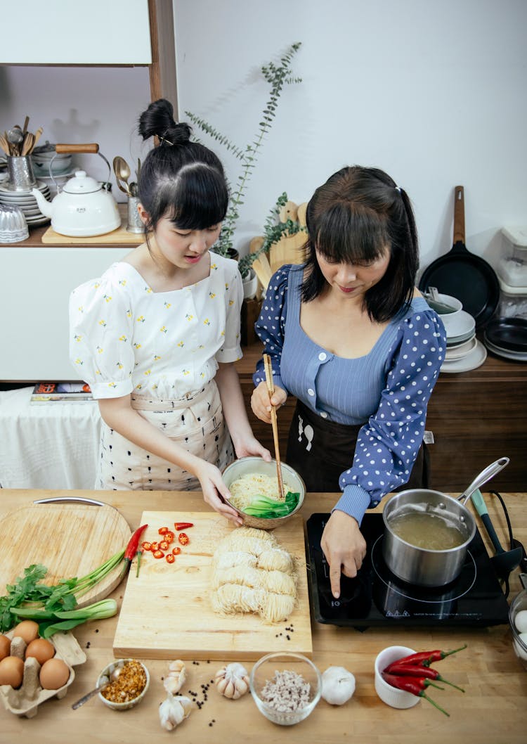 Positive Asian Women Adding Pak Choi Cabbage Into Noodle Soup