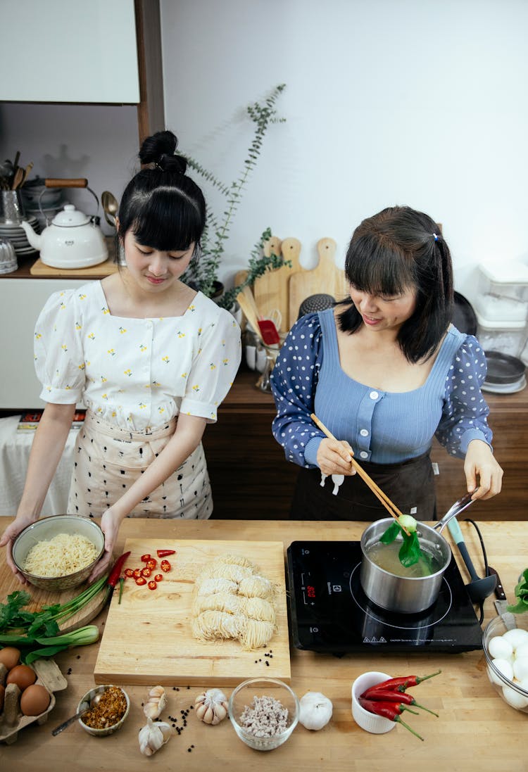 Glad Asian Women Adding Boiled Pak Choi To Noodles