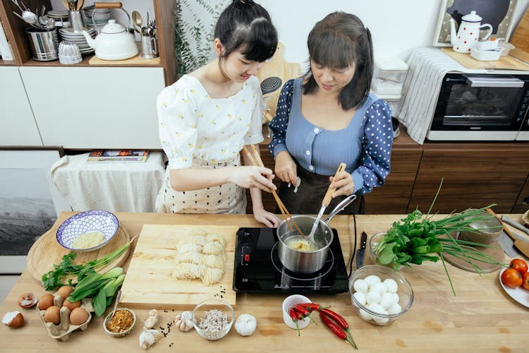 Positive Asian Women Boiling Noodles In Saucepan