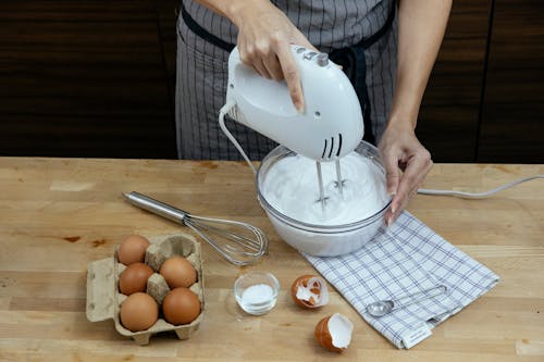 투명 유리 그릇에 갈색 계란을 붓는 흰색 플라스틱 투 수를 들고 사람