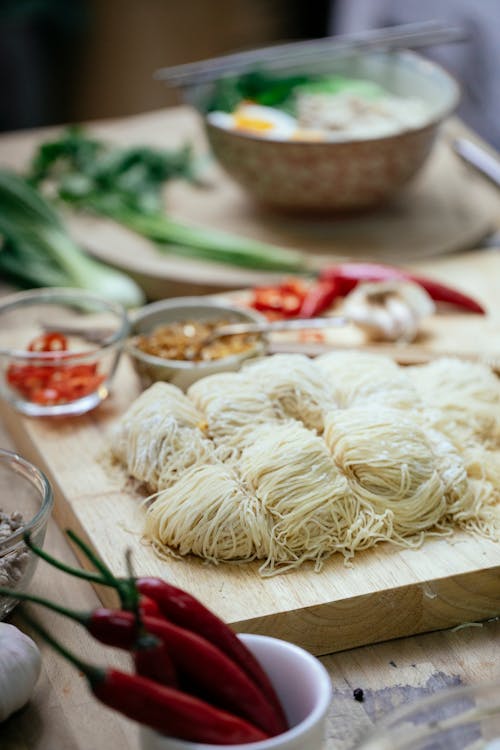 Free Composition of fresh ingredients for cooking traditional Asian soup including homemade noodles peppers and vegetables on kitchen table Stock Photo