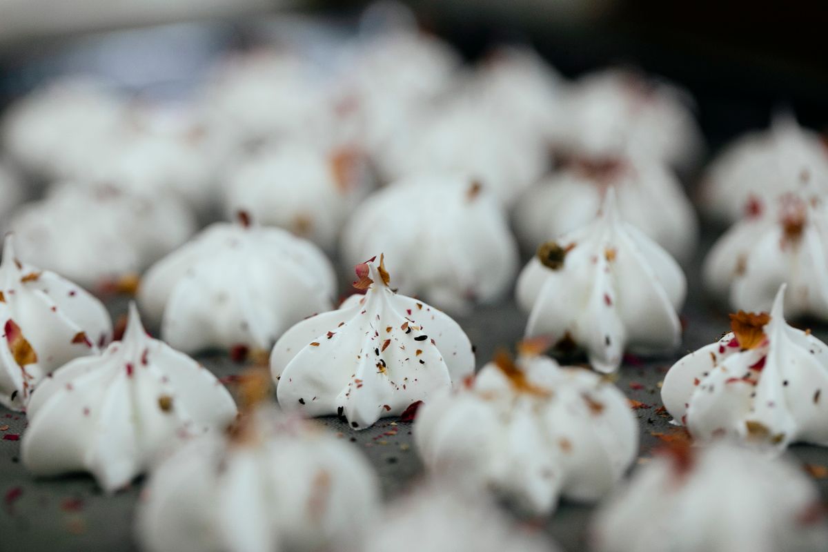 Sweet vanilla meringue cookies arranged on baking pan covered with tasty chocolate powder in modern bakery