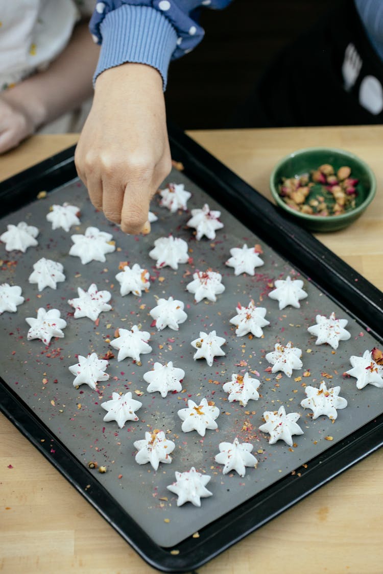 Anonymous Woman Decorating Christmas Meringue Cookies In Kitchen