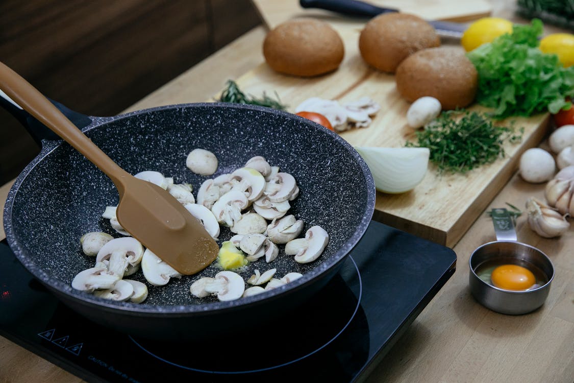 Free Chopped mushrooms in frying pan placed on stove near various veggies and herbs Stock Photo
