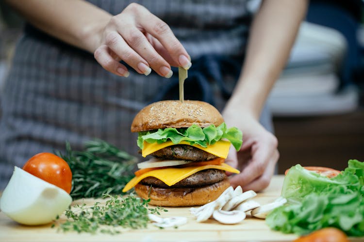 Crop Woman With Burger In Kitchen