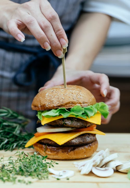 Crop woman serving delicious burger