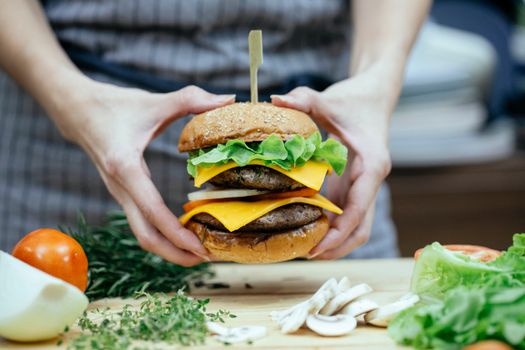 Crop woman with burger at table