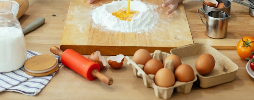 Unrecognizable person mixing egg into flour at table with wooden board rolling pin and kitchenware in light kitchen while cooking