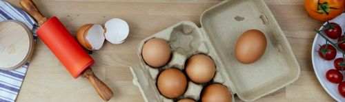 Free Top view of eggs and eggshell on wooden table with rolling pin and tomatoes placed in kitchen during cooking process Stock Photo