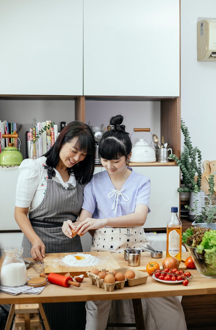 Cheerful Asian Women Adding Egg To Flour