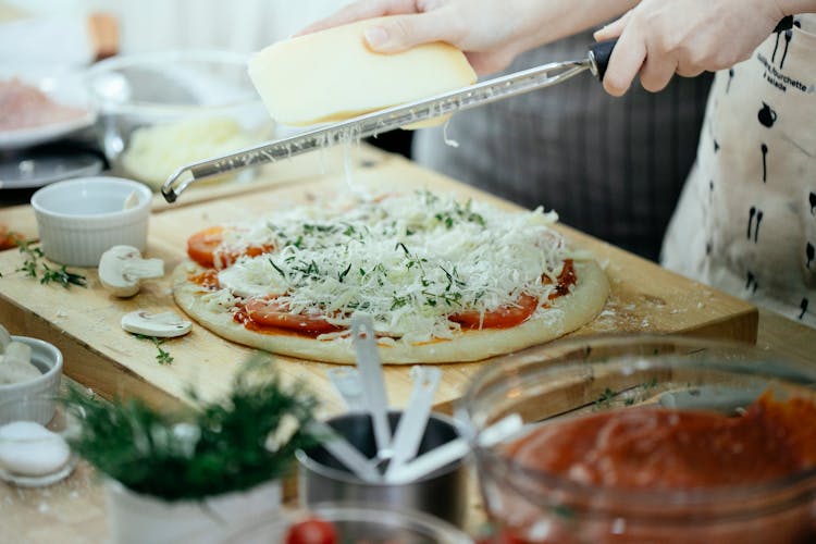 Crop Woman Rubbing Cheese On Pizza