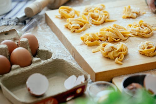 Free Raw tagliatelle nests on wooden board Stock Photo