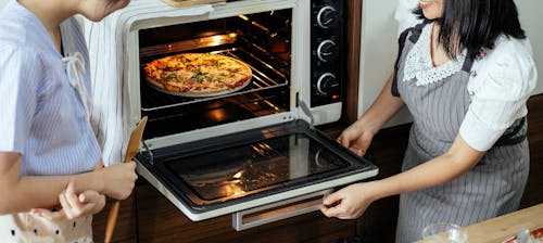 Free Crop women putting pizza in oven Stock Photo