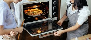 Crop women putting pizza in oven