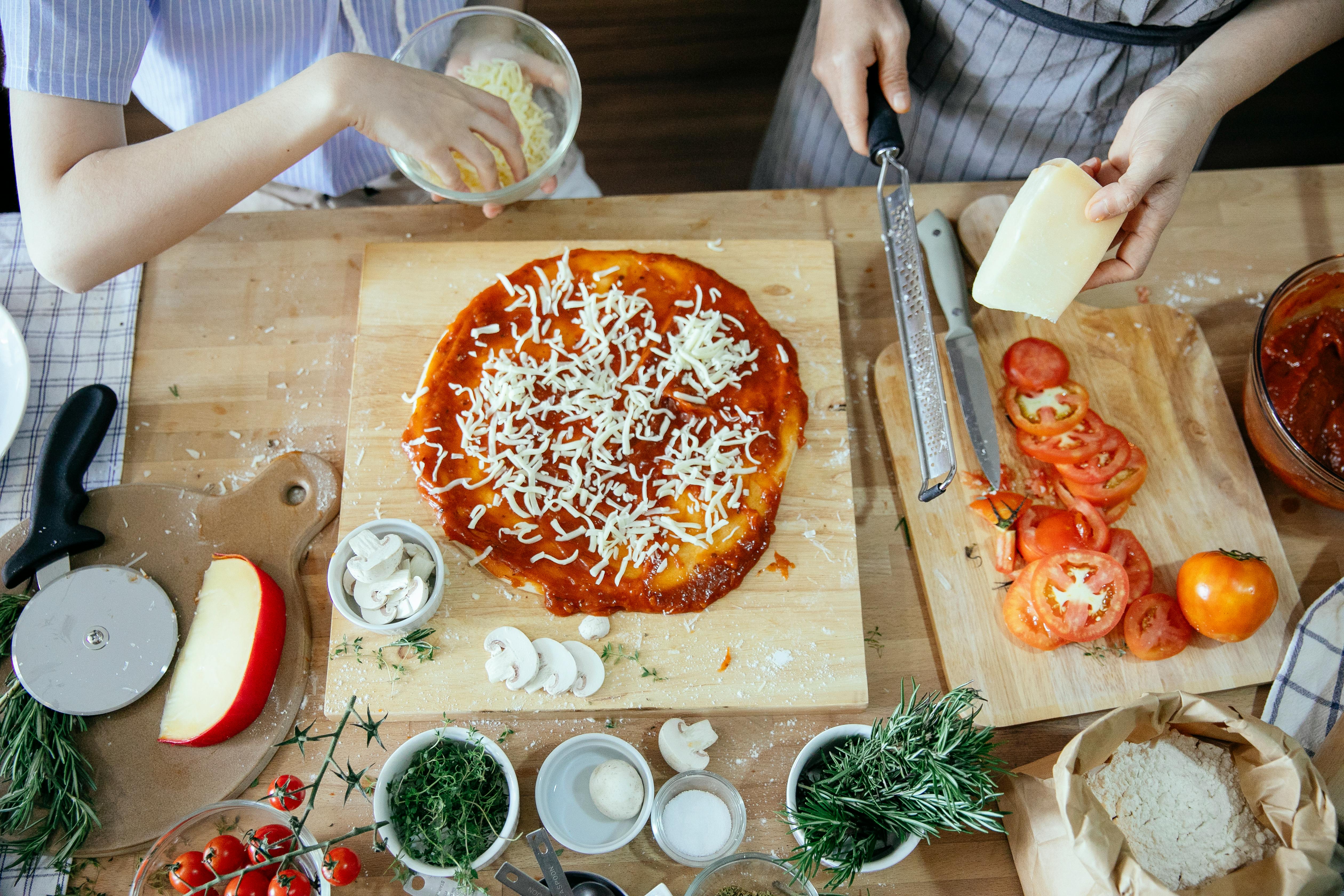 crop women adding cheese on pizza