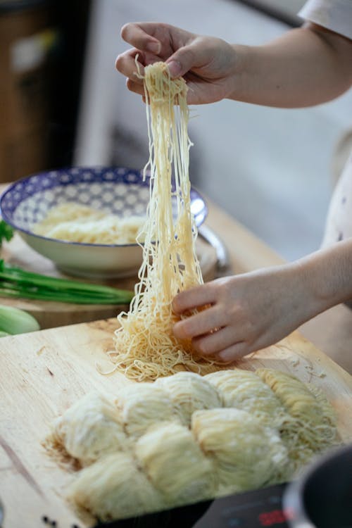 持有黃色麵食棕色木製的桌子上的人