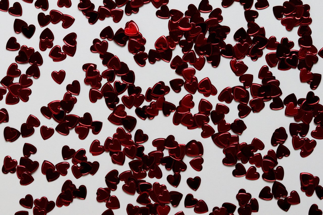 a close up of scattered red heart shaped confetti on a white surface i
